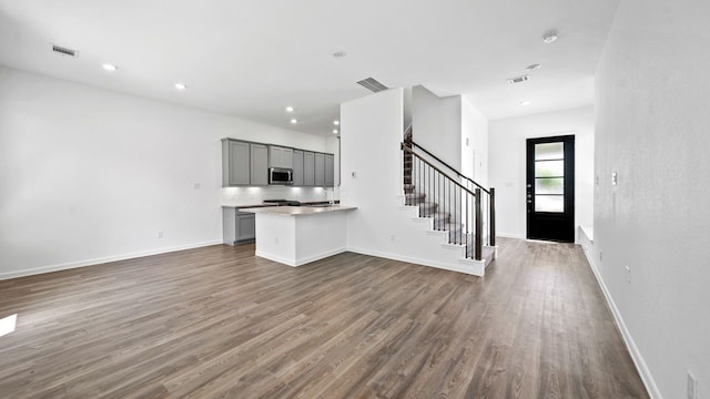 interior space with kitchen peninsula, gray cabinets, dark hardwood / wood-style flooring, and backsplash