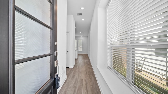 hall featuring plenty of natural light and light hardwood / wood-style flooring