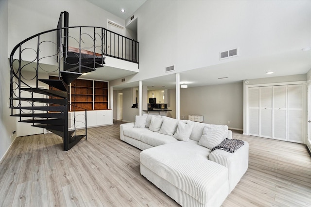 living room with a towering ceiling and light wood-type flooring