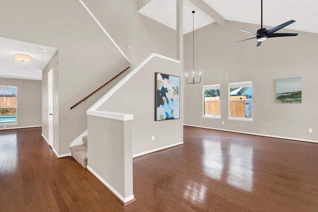 unfurnished living room featuring beamed ceiling, dark wood-type flooring, and a wealth of natural light