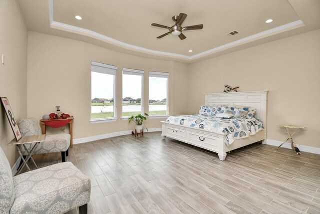 bedroom featuring a tray ceiling, ceiling fan, crown molding, and light hardwood / wood-style floors