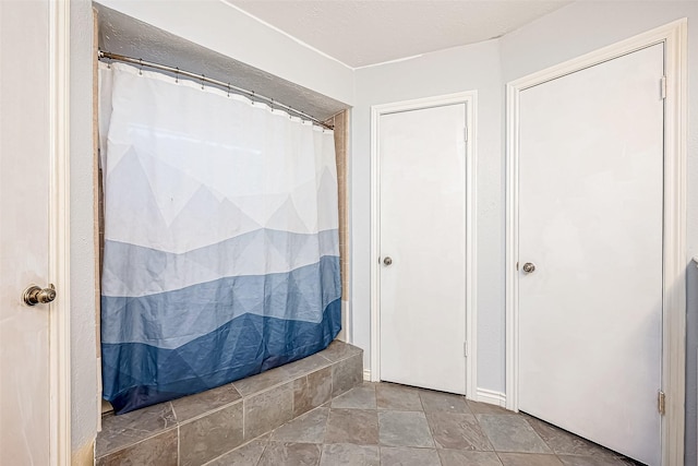 bathroom featuring a shower with curtain and stone finish floor