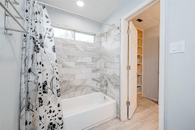 bathroom featuring shower / bath combo and wood finish floors