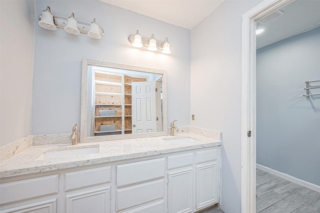 full bathroom featuring visible vents, a sink, baseboards, and double vanity