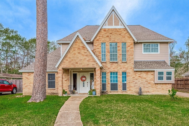 view of front of property with a front lawn, roof with shingles, and fence