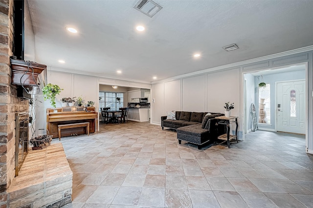 living room with crown molding, visible vents, and a decorative wall