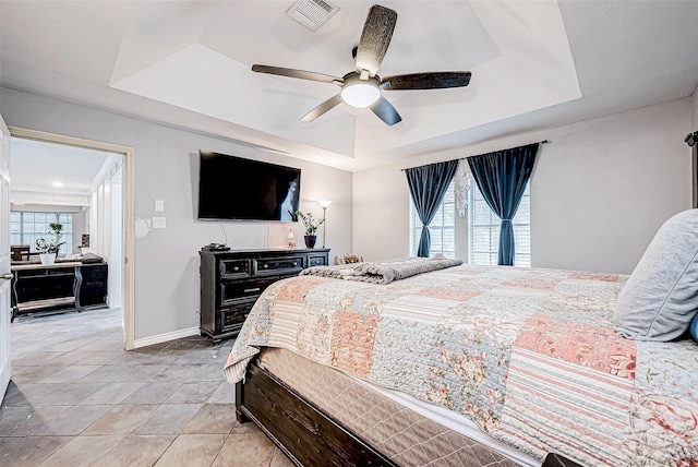 tiled bedroom featuring a tray ceiling and ceiling fan