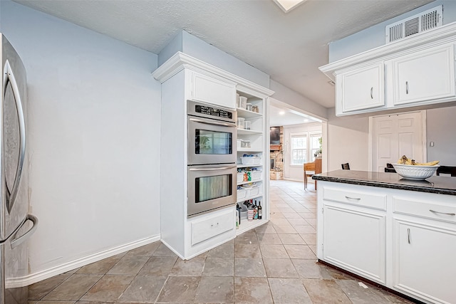 kitchen featuring dark countertops, white cabinetry, and stainless steel appliances