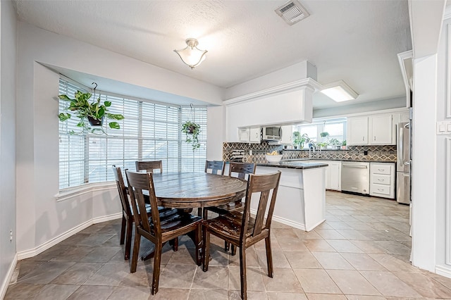 dining room with baseboards, visible vents, a textured ceiling, and light tile patterned flooring