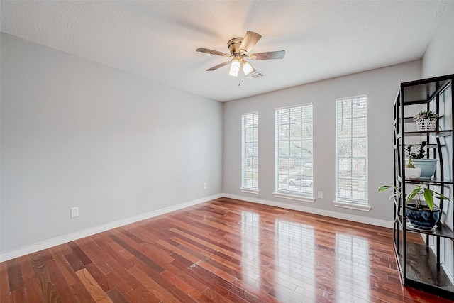 empty room with baseboards, visible vents, and dark wood-type flooring