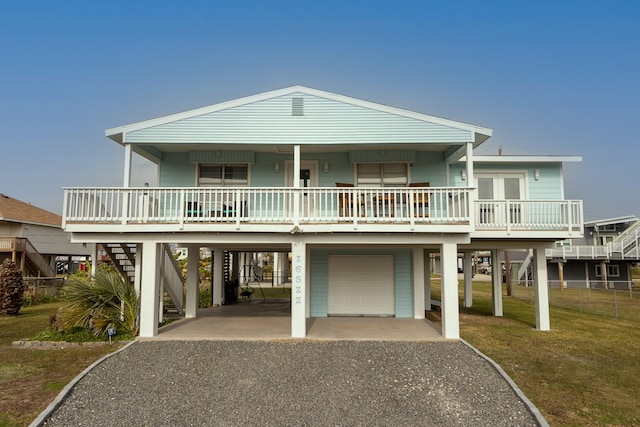 view of front of home featuring covered porch, a carport, a garage, and a front lawn