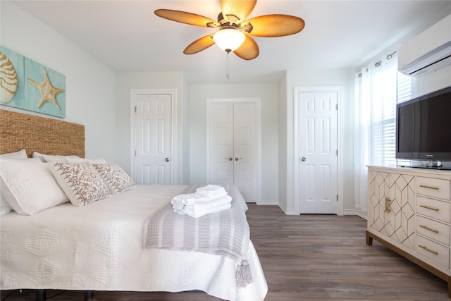 bedroom with dark wood-type flooring, a wall mounted air conditioner, ceiling fan, and multiple closets