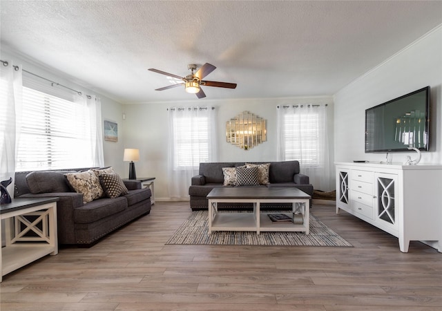 living room with a textured ceiling, ornamental molding, hardwood / wood-style flooring, and ceiling fan