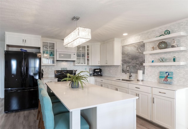 kitchen with white cabinetry, decorative light fixtures, a kitchen island, black appliances, and sink