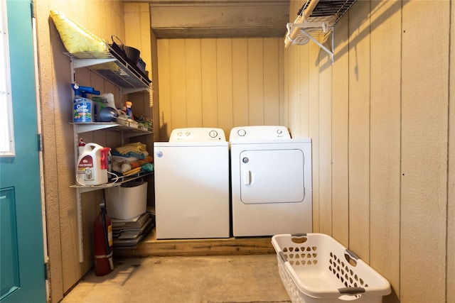 clothes washing area featuring independent washer and dryer and wooden walls