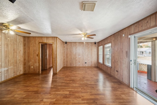 interior space with hardwood / wood-style floors, ceiling fan, wood walls, and a textured ceiling