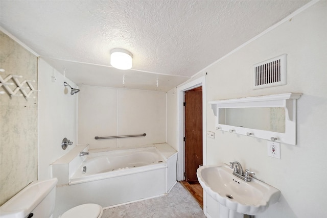 bathroom featuring a textured ceiling, a tub to relax in, toilet, and sink