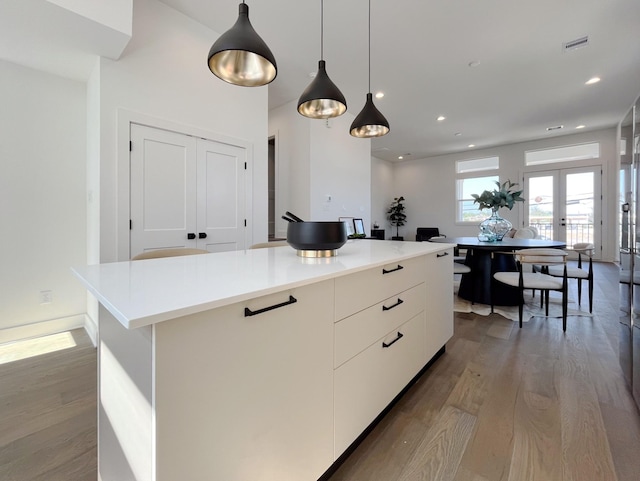 kitchen featuring white cabinets, french doors, a kitchen island, and hanging light fixtures