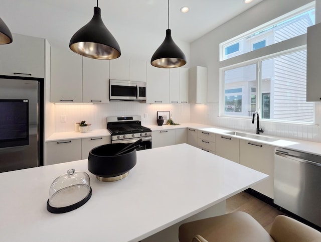 kitchen with backsplash, white cabinetry, stainless steel appliances, and hanging light fixtures