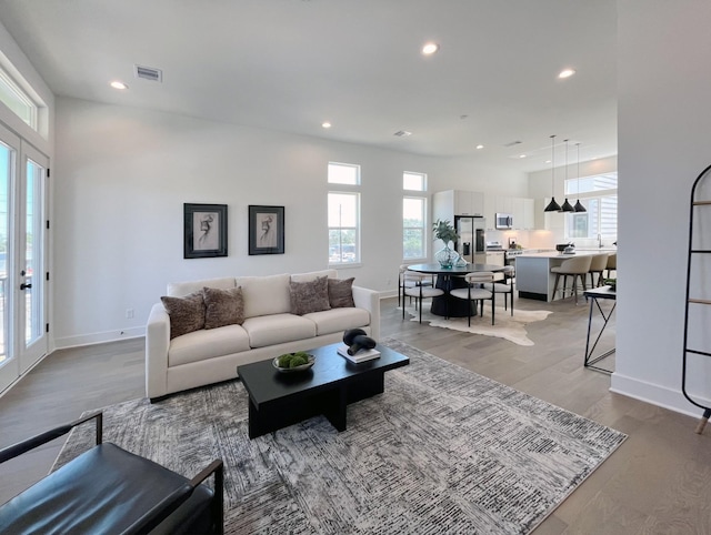 living room featuring a high ceiling, light wood-type flooring, and plenty of natural light