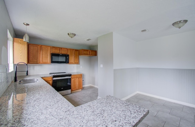 kitchen featuring light stone counters, sink, decorative light fixtures, stainless steel electric range oven, and light tile patterned flooring