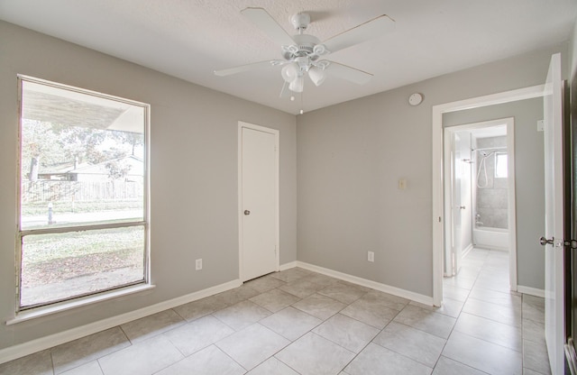 spare room with ceiling fan, light tile patterned floors, and a textured ceiling