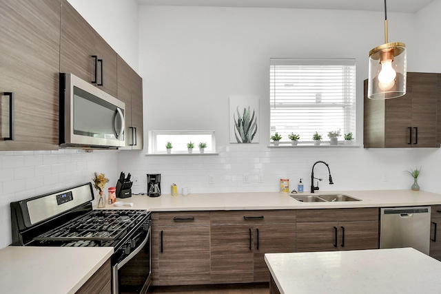 kitchen with decorative light fixtures, decorative backsplash, sink, and appliances with stainless steel finishes