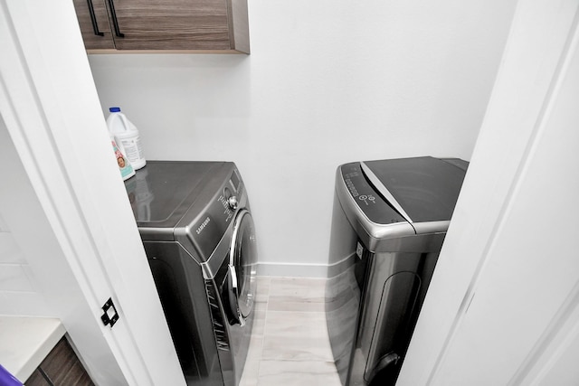 clothes washing area with cabinets and separate washer and dryer