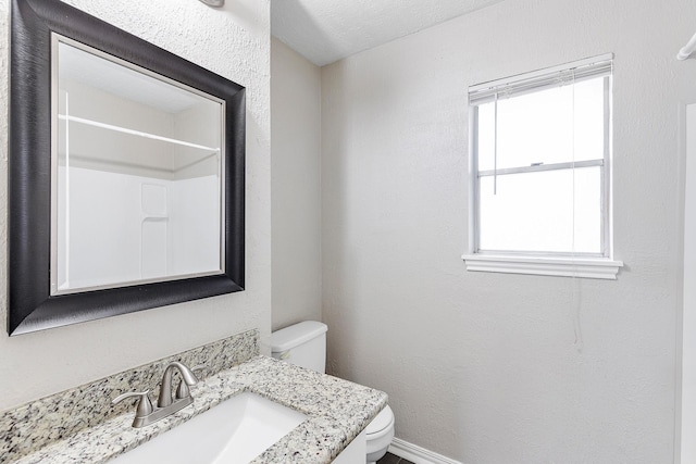 bathroom featuring a textured ceiling, vanity, and toilet