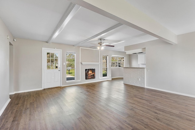 unfurnished living room with beamed ceiling, dark hardwood / wood-style floors, a brick fireplace, and ceiling fan