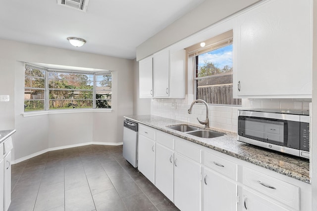 kitchen with backsplash, white cabinets, sink, appliances with stainless steel finishes, and light stone counters