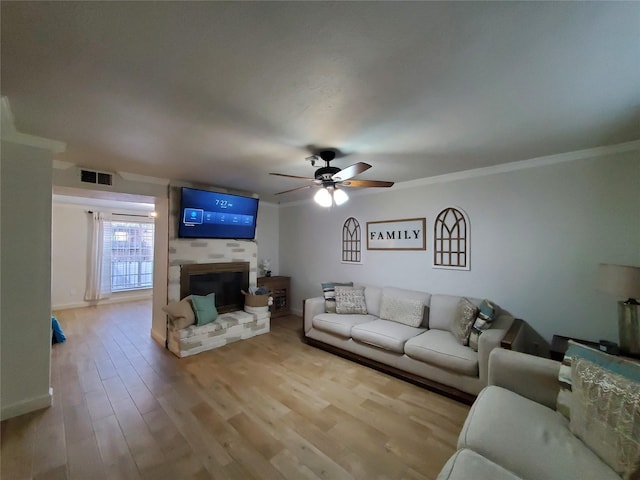 living room featuring crown molding, a fireplace, ceiling fan, and light hardwood / wood-style floors