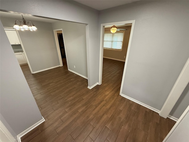 interior space featuring ceiling fan with notable chandelier and dark hardwood / wood-style floors