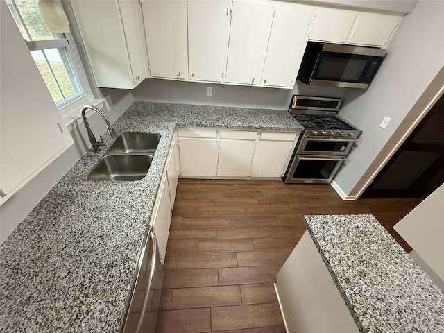 kitchen featuring dark wood-type flooring, white cabinets, sink, appliances with stainless steel finishes, and light stone counters