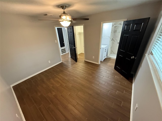 unfurnished bedroom with dark wood-type flooring, ensuite bath, ceiling fan, a spacious closet, and a closet