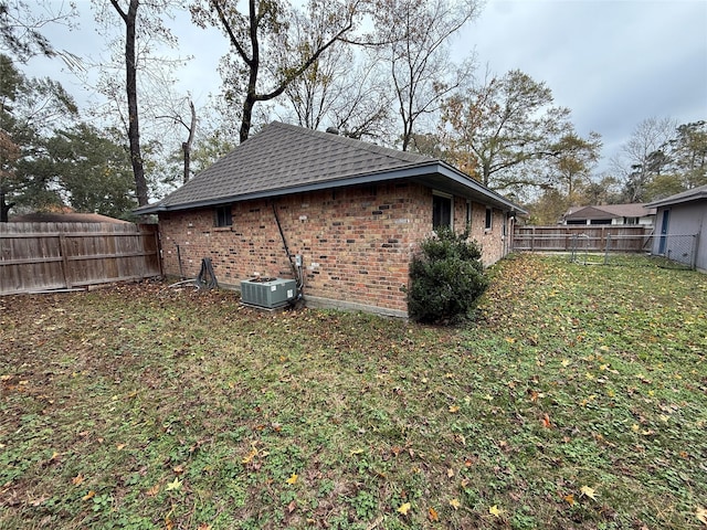 view of side of property featuring a yard and central AC