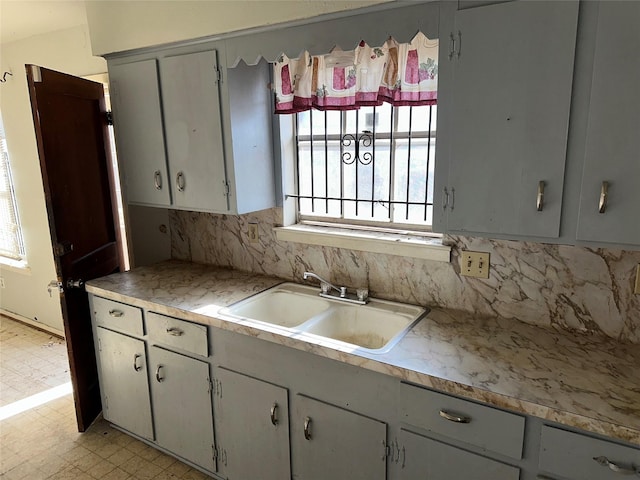 kitchen with backsplash, gray cabinets, and sink