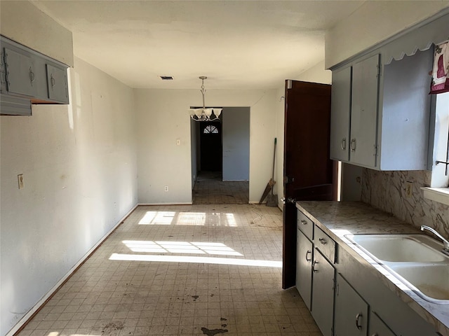 kitchen featuring gray cabinets, sink, decorative light fixtures, and a notable chandelier