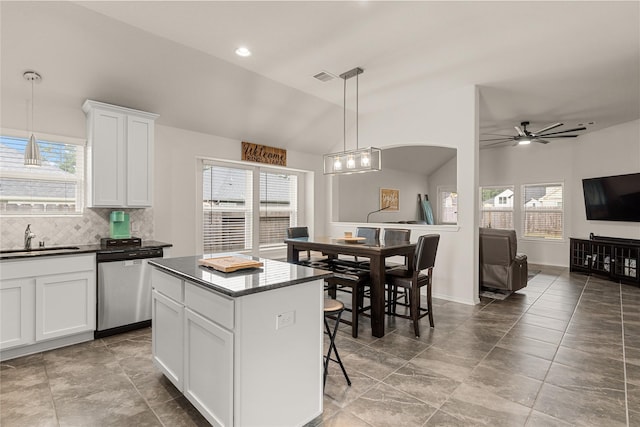 kitchen featuring white cabinetry, sink, stainless steel dishwasher, lofted ceiling, and a kitchen island