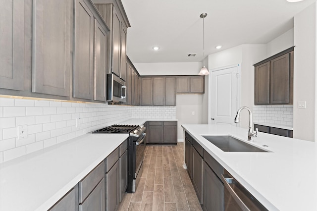 kitchen featuring sink, appliances with stainless steel finishes, backsplash, hanging light fixtures, and dark brown cabinets