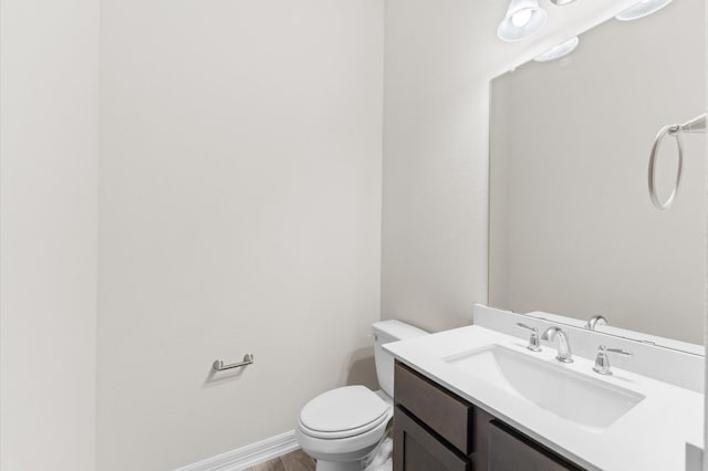 bathroom with hardwood / wood-style flooring, vanity, and toilet