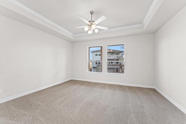 spare room with a tray ceiling, ornamental molding, ceiling fan, and carpet