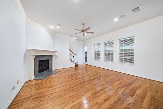 unfurnished living room with light hardwood / wood-style floors, ornamental molding, ceiling fan, and a fireplace