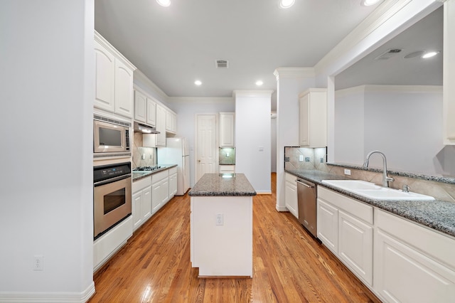 kitchen with white cabinets, a center island, stainless steel appliances, sink, and stone countertops