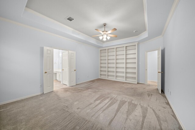 unfurnished bedroom featuring ornamental molding, light colored carpet, ceiling fan, and a raised ceiling