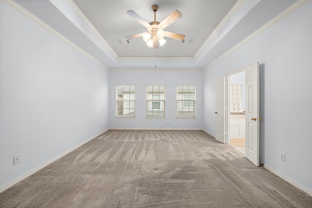 unfurnished room with light carpet, ceiling fan, a tray ceiling, and crown molding