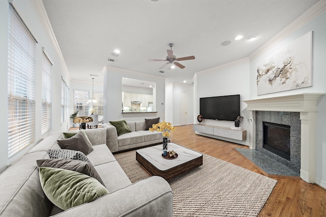 living room featuring wood-type flooring, ceiling fan, crown molding, and a premium fireplace