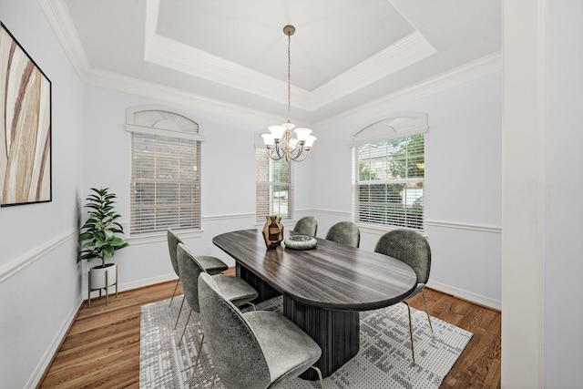 dining space with dark hardwood / wood-style flooring, an inviting chandelier, a raised ceiling, and crown molding