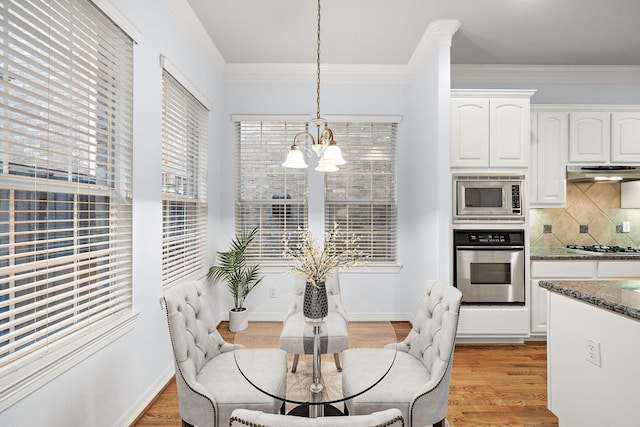 dining area with light hardwood / wood-style flooring, crown molding, and a notable chandelier