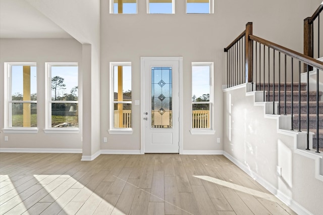 entrance foyer with a towering ceiling and light wood-type flooring